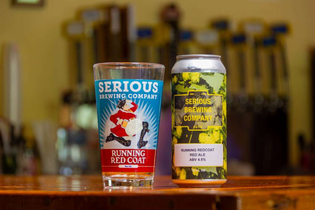 "Running Red Coat" beer in a can, next to a glass with artwork of a man running in a red coat.