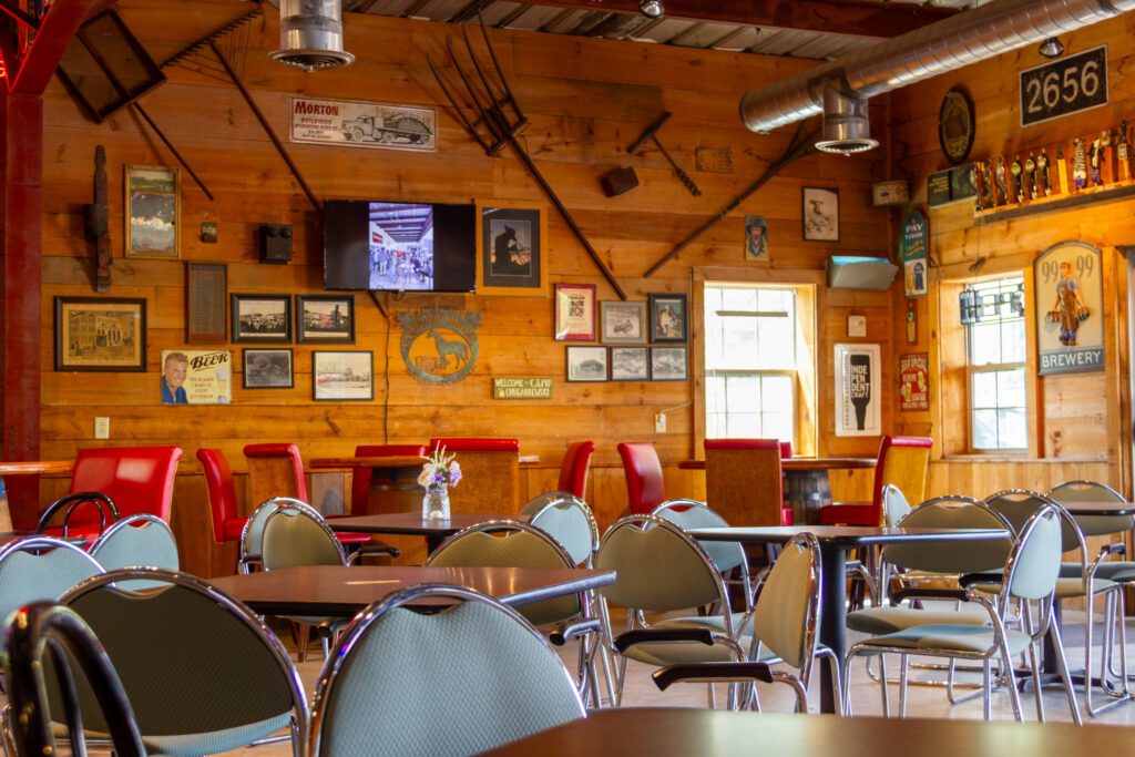 Serious Brewing Co.'s cozy brewery tasting room featuring warm wooden walls and tables with chairs arranged around the room.